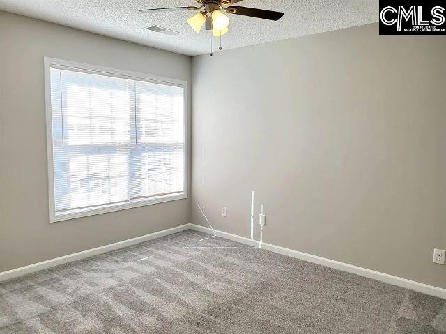 carpeted spare room with ceiling fan and a textured ceiling