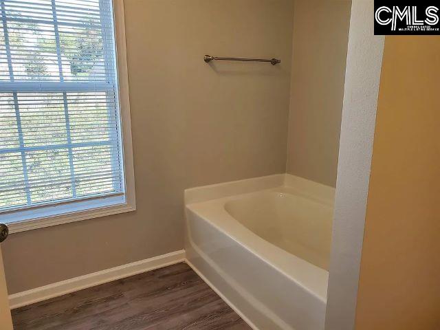 bathroom with hardwood / wood-style floors, a wealth of natural light, and a bathing tub