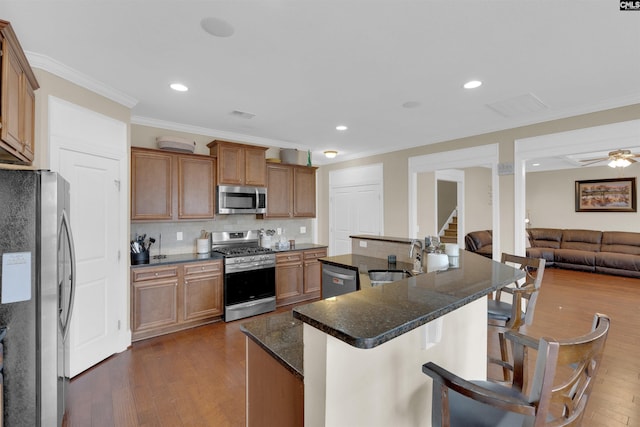 kitchen with sink, dark wood-type flooring, backsplash, appliances with stainless steel finishes, and ornamental molding