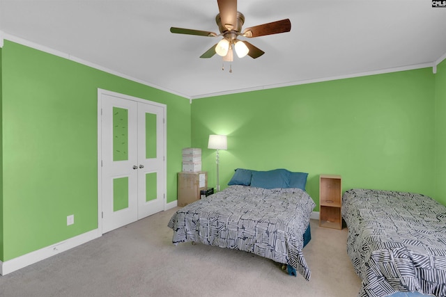 carpeted bedroom with a closet, ceiling fan, and ornamental molding