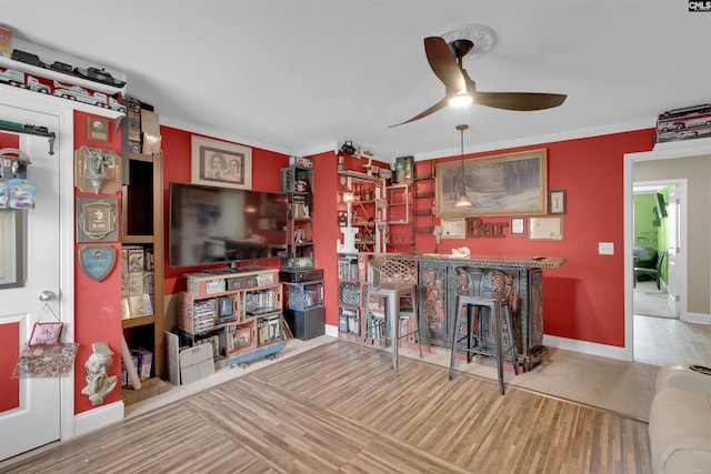 interior space featuring bar area, hardwood / wood-style flooring, ceiling fan, and ornamental molding