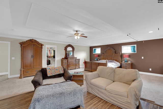 living room with ceiling fan, light hardwood / wood-style floors, and a tray ceiling