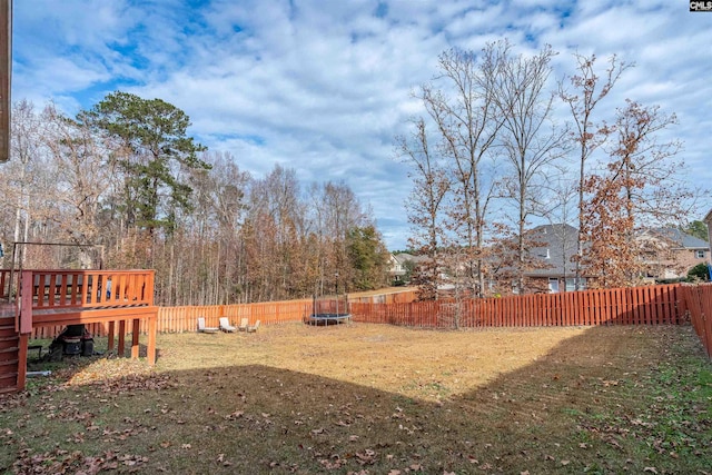 view of yard with a wooden deck and a trampoline