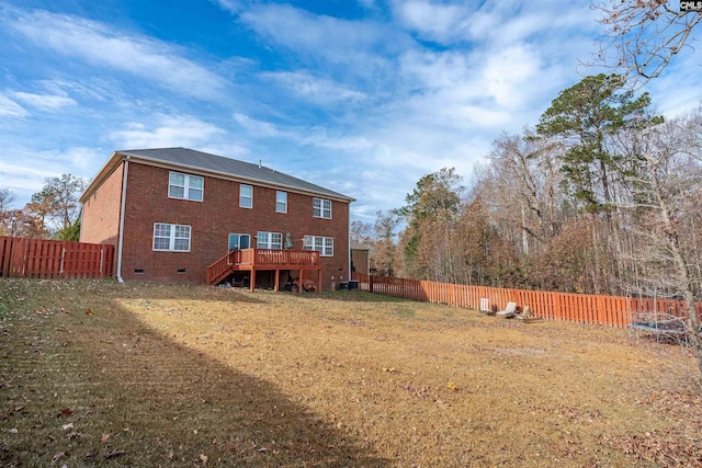 back of house featuring a lawn, a deck, and a trampoline