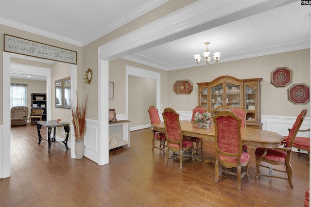 dining room with hardwood / wood-style floors, ornamental molding, and a chandelier