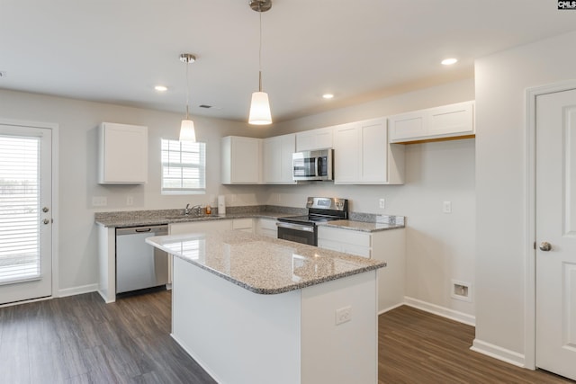 kitchen featuring a center island, dark wood-type flooring, stainless steel appliances, light stone counters, and white cabinets