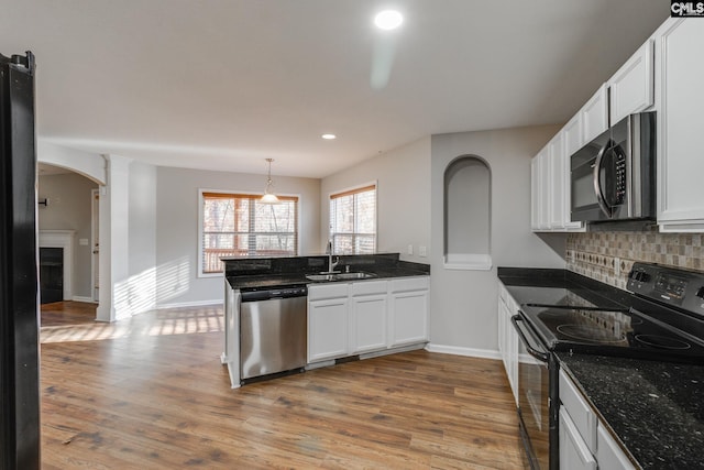 kitchen with wood-type flooring, stainless steel appliances, white cabinetry, and sink