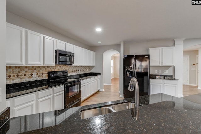 kitchen with black appliances, dark stone countertops, white cabinetry, and sink