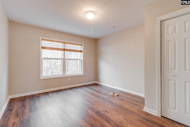 spare room with a textured ceiling and dark hardwood / wood-style floors