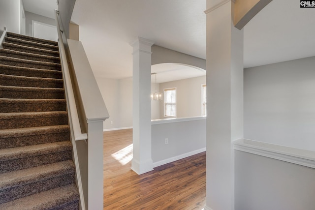 stairway featuring hardwood / wood-style floors and an inviting chandelier