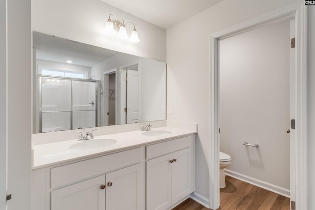 bathroom with hardwood / wood-style floors, vanity, a shower with shower door, and toilet