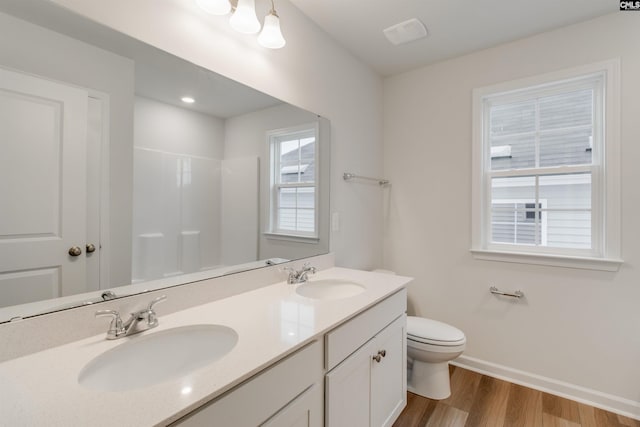 bathroom with hardwood / wood-style flooring, vanity, toilet, and a shower