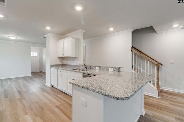 kitchen featuring light wood-type flooring, light stone counters, white cabinetry, and sink