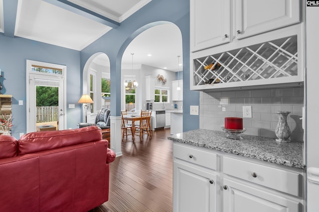 kitchen with decorative backsplash, white cabinetry, stainless steel dishwasher, and dark hardwood / wood-style floors