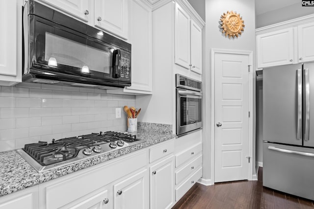 kitchen featuring light stone counters, dark hardwood / wood-style flooring, decorative backsplash, white cabinets, and appliances with stainless steel finishes