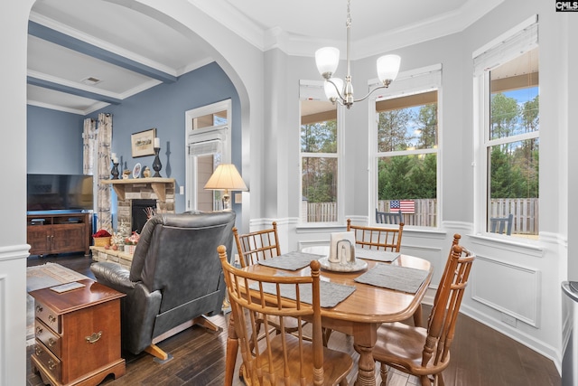 dining area with a fireplace, dark hardwood / wood-style floors, an inviting chandelier, and ornamental molding