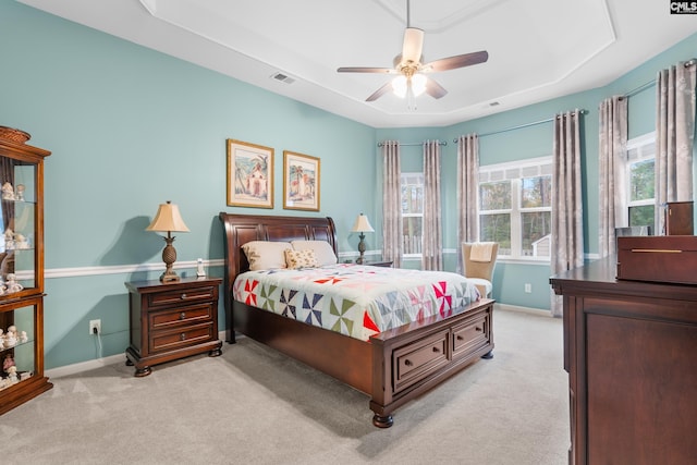 bedroom featuring a tray ceiling, ceiling fan, and light colored carpet