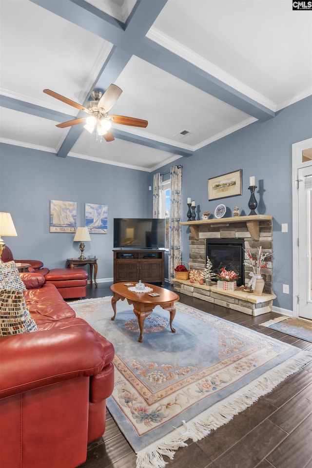 living room with dark hardwood / wood-style flooring, ornamental molding, ceiling fan, beam ceiling, and a stone fireplace