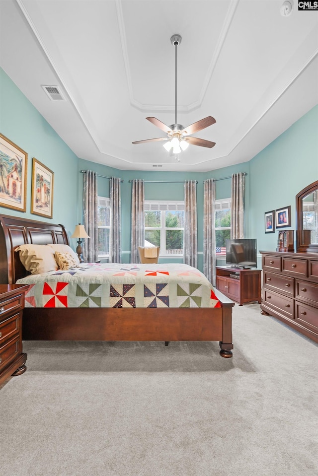 carpeted bedroom with ceiling fan and a raised ceiling