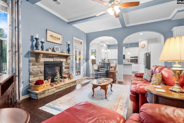 living room featuring ceiling fan, a stone fireplace, beamed ceiling, dark hardwood / wood-style floors, and ornamental molding