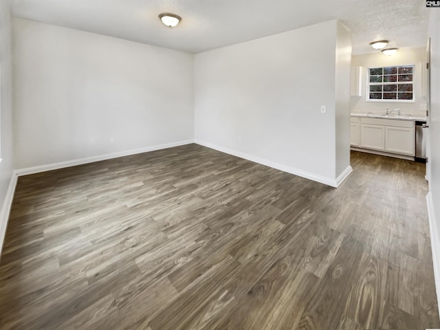 empty room featuring a textured ceiling, dark hardwood / wood-style floors, and sink