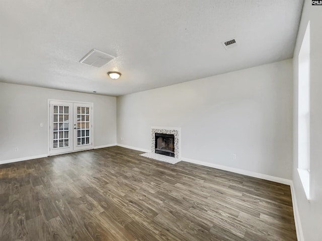 unfurnished living room featuring french doors, a textured ceiling, and dark wood-type flooring