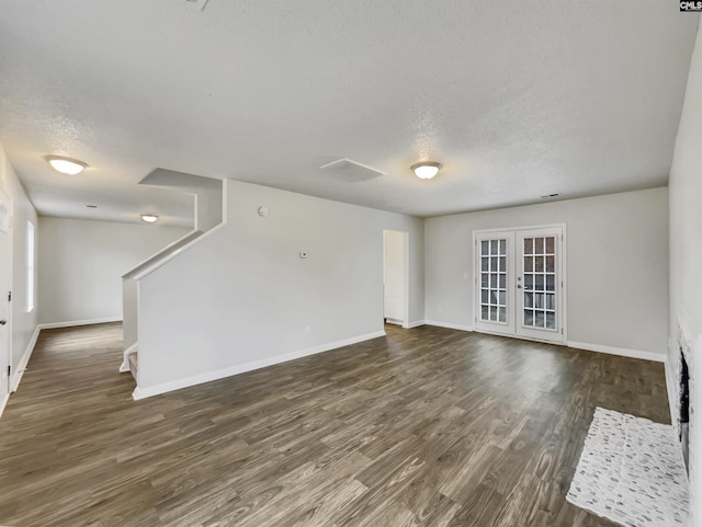 unfurnished living room featuring french doors, dark hardwood / wood-style flooring, and a textured ceiling