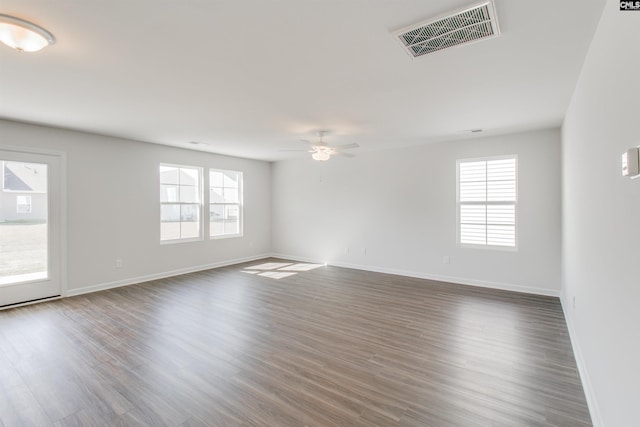 unfurnished room featuring dark wood-style floors, baseboards, visible vents, and a wealth of natural light