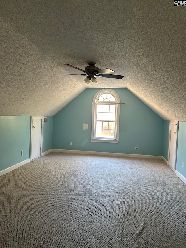 additional living space with vaulted ceiling, ceiling fan, light colored carpet, and a textured ceiling