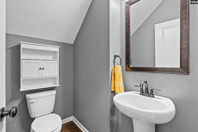 bathroom with hardwood / wood-style flooring, sink, lofted ceiling, and toilet