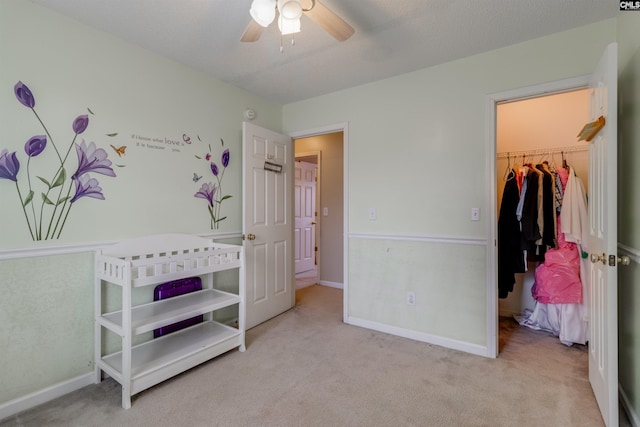 bedroom with a walk in closet, ceiling fan, a closet, and light colored carpet