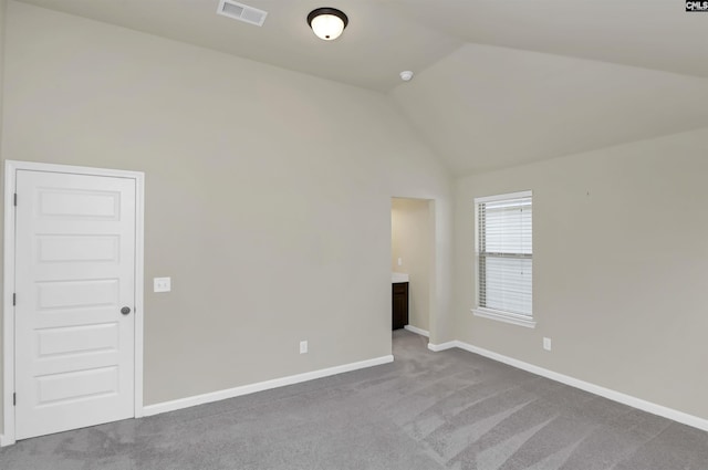 carpeted empty room with vaulted ceiling