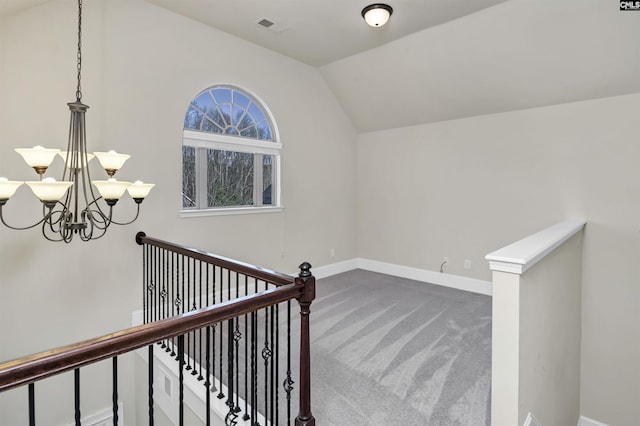 hallway featuring carpet, a chandelier, and vaulted ceiling