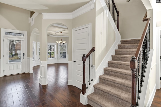 foyer entrance with ornamental molding, coffered ceiling, a chandelier, beamed ceiling, and dark hardwood / wood-style floors