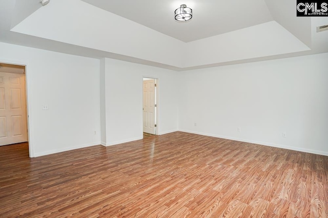 unfurnished room with hardwood / wood-style floors and a tray ceiling