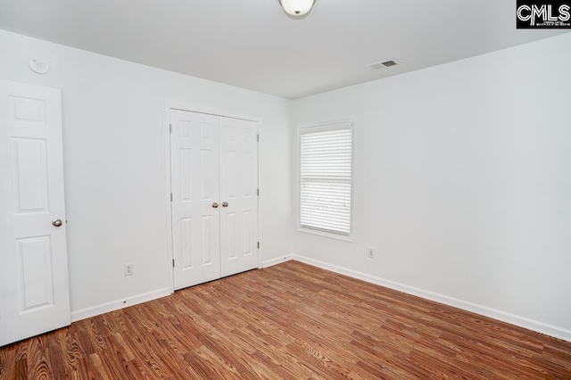 unfurnished bedroom with hardwood / wood-style flooring and a closet