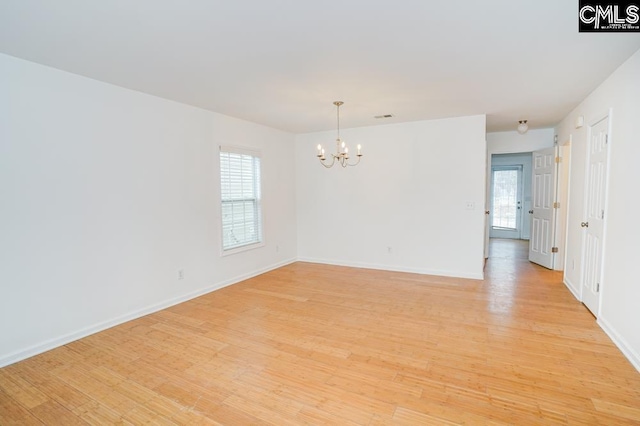 unfurnished room featuring light hardwood / wood-style floors and an inviting chandelier