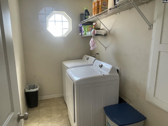 washroom with laundry area, washer and clothes dryer, baseboards, and light tile patterned floors