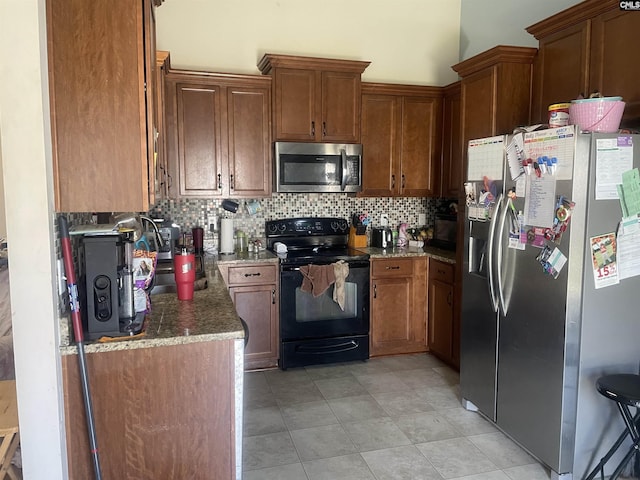 kitchen featuring stainless steel appliances, dark stone counters, brown cabinets, and decorative backsplash