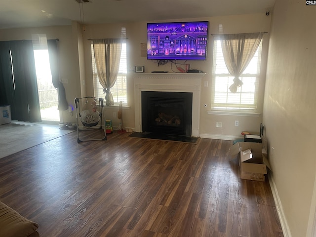 unfurnished living room featuring a wealth of natural light, a fireplace, baseboards, and wood finished floors