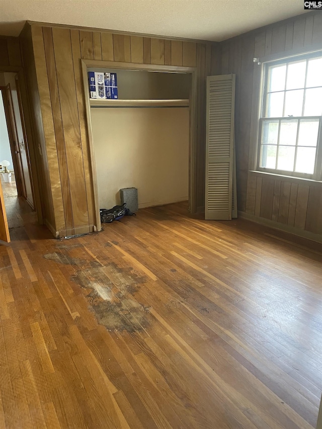 unfurnished bedroom featuring a closet, wooden walls, and hardwood / wood-style flooring