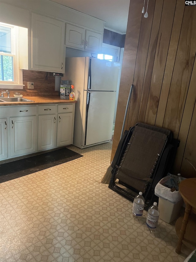 kitchen featuring light floors, white cabinetry, a sink, and freestanding refrigerator