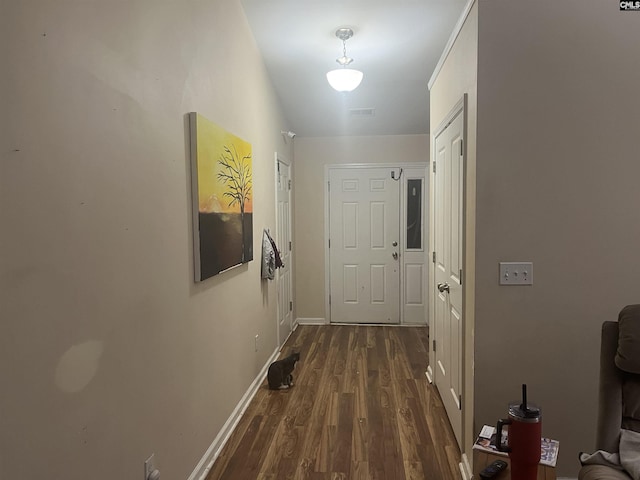 hallway featuring dark wood-type flooring, visible vents, and baseboards