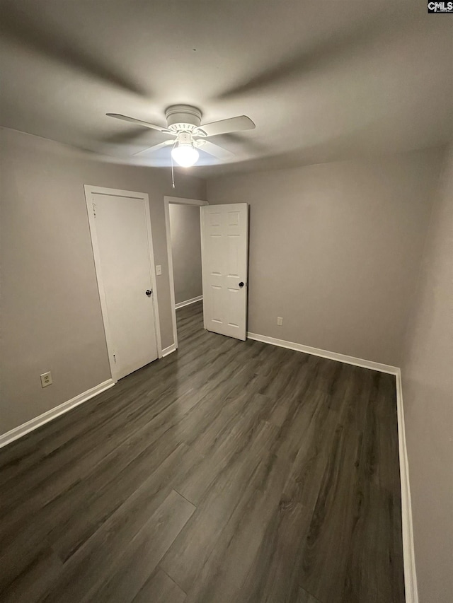 unfurnished room with ceiling fan and dark wood-type flooring