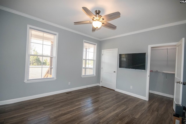 unfurnished living room featuring ceiling fan, a healthy amount of sunlight, ornamental molding, and dark wood-type flooring