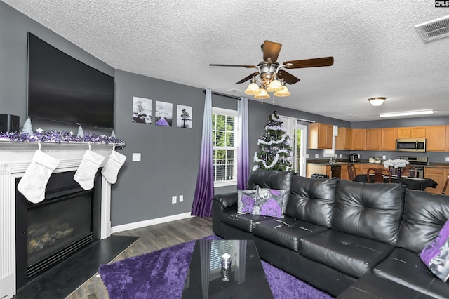 living room featuring a textured ceiling, ceiling fan, and dark wood-type flooring