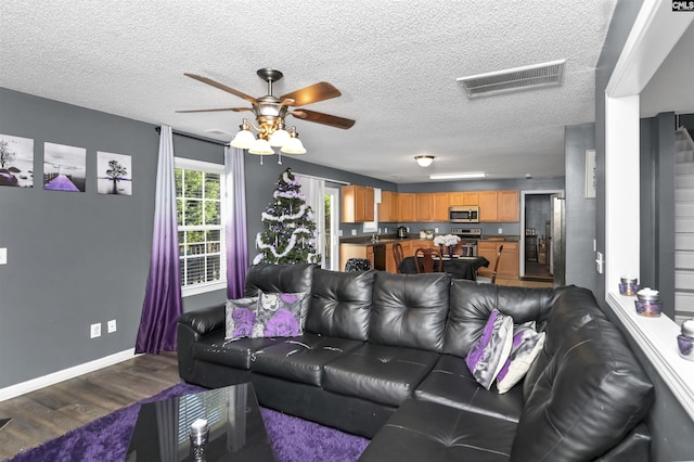 living room with hardwood / wood-style flooring, ceiling fan, and a textured ceiling