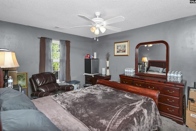 carpeted bedroom with ceiling fan and a textured ceiling