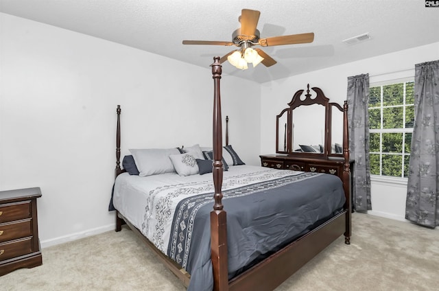 bedroom featuring a textured ceiling, light colored carpet, and ceiling fan