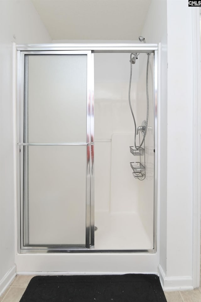 bathroom featuring tile patterned flooring, a shower with door, and vaulted ceiling